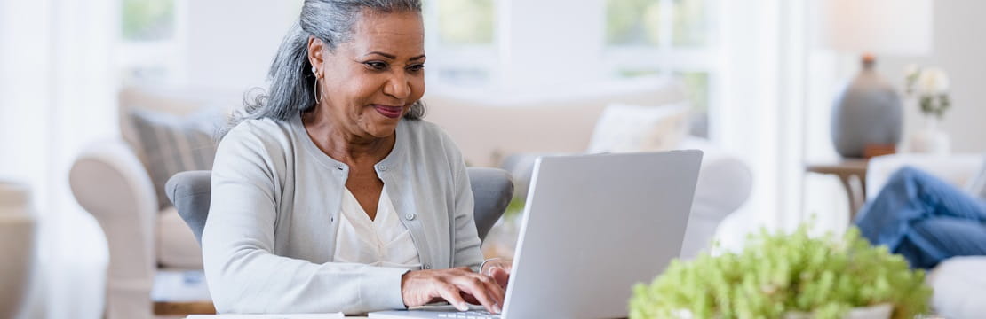 Black woman sits at her computer answering emails.